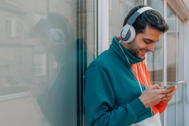 Sokakta cep telefonu ve kulaklığı olan genç bir adam.