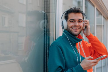 Sokakta cep telefonu ve kulaklığı olan genç bir adam.