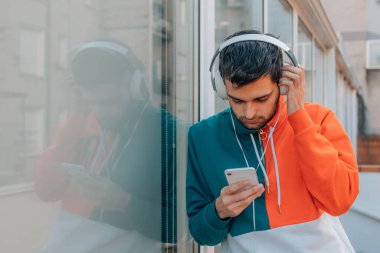 Sokaktaki genç adam cep telefonu ve kulaklığı ile