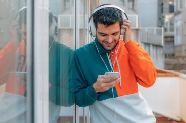 Sokaktaki genç adam cep telefonu ve kulaklığı ile