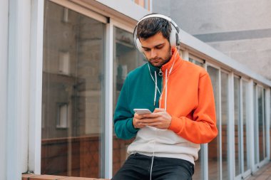 Sokaktaki genç adam cep telefonu ve kulaklığı ile