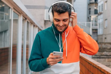 Sokaktaki genç adam cep telefonu ve kulaklığı ile