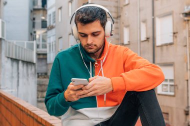 Sokaktaki genç adam cep telefonu ve kulaklığı ile