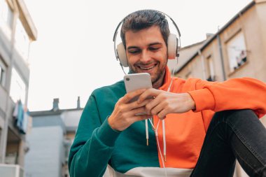 Sokaktaki genç adam cep telefonu ve kulaklığı ile