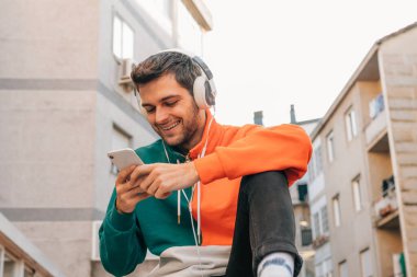 Sokaktaki genç adam cep telefonu ve kulaklığı ile