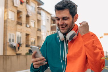 Sokakta cep telefonu ve kulaklığı olan başarılı bir ifadesi olan bir adam.