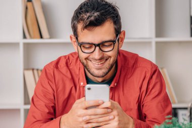 Evde ya da ofiste cep telefonu olan bir adam.