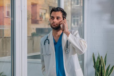 Cep telefonu olan genç bir doktor.