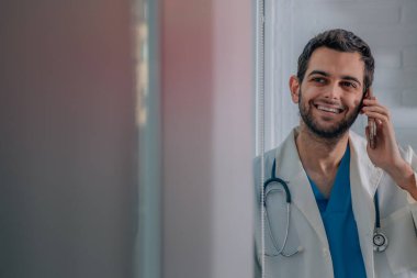 Cep telefonu olan genç bir doktor.