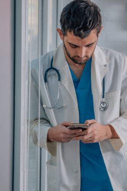Cep telefonu olan genç bir doktor.