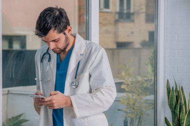 Elinde cep telefonu olan bir doktor.