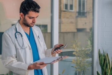 Elinde cep telefonu olan bir doktor.