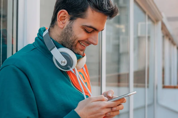 young man in the street with mobile phone and headphones