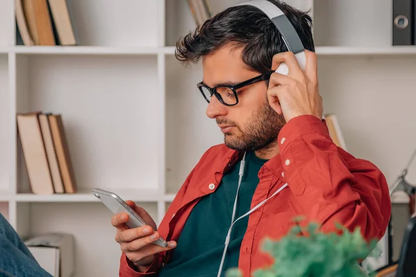 Άνθρωπος Στο Σπίτι Ακούγοντας Μουσική Ακουστικά Και Κινητό Τηλέφωνο — Φωτογραφία Αρχείου