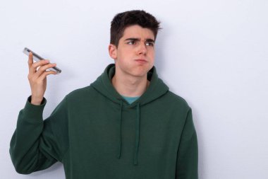 Delikanlı, boş bir odada stres dolu sesli mesajlar dinliyor.