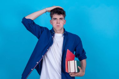 Kitapları olan öğrenci mavi arka planda izole edilmiş