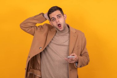 Cep telefonu ve sürpriz ifadesi olan izole bir genç adam.