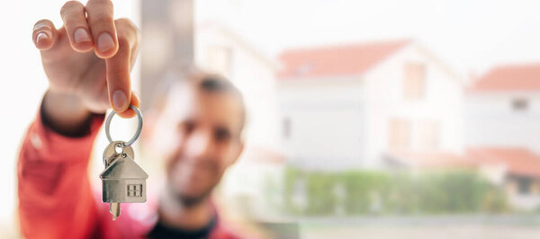 man with keys in hand, buy house or rent