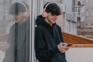 Sokaklarda cep telefonu ve kulaklığı olan bin yıllık genç adam.