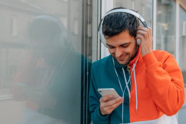 Sokaktaki genç adam cep telefonu ve kulaklığı ile