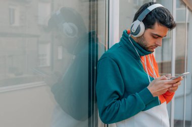 Sokakta cep telefonu ve kulaklığı olan genç bir adam.