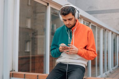 Sokaktaki genç adam cep telefonu ve kulaklığı ile