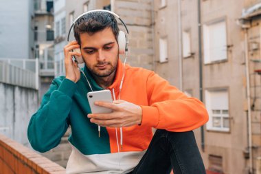 Sokaktaki genç adam cep telefonu ve kulaklığı ile