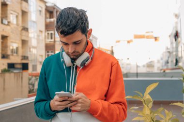 Sokaktaki genç adam cep telefonuna bakıyor.