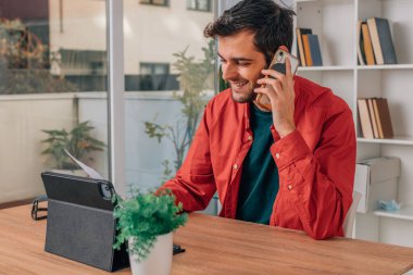 Bilgisayarı ve cep telefonu olan genç bir adam.