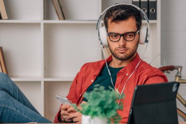 man at home listening to music with headphones and mobile phone