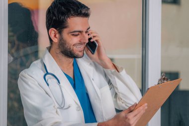 Doktor cep telefonu ve belgelerle çalışıyor.