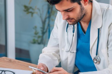 Üniformalı genç doktor ve cep telefonlu steteskop.