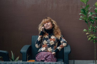 Orta yaşlı bir kadın cep telefonuyla konuşuyor.