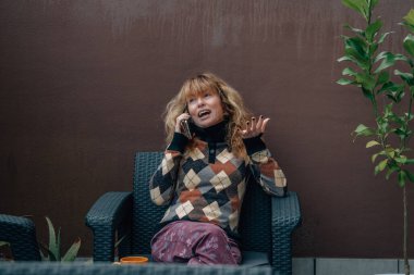 Orta yaşlı bir kadın cep telefonuyla konuşuyor.