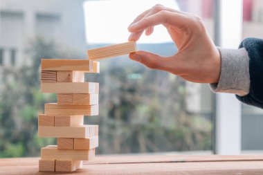 hand with wooden piece in puzzle tower