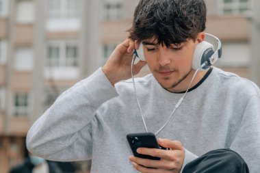 Sokaklarda cep telefonu ve kulaklığı olan genç bir çocuk.