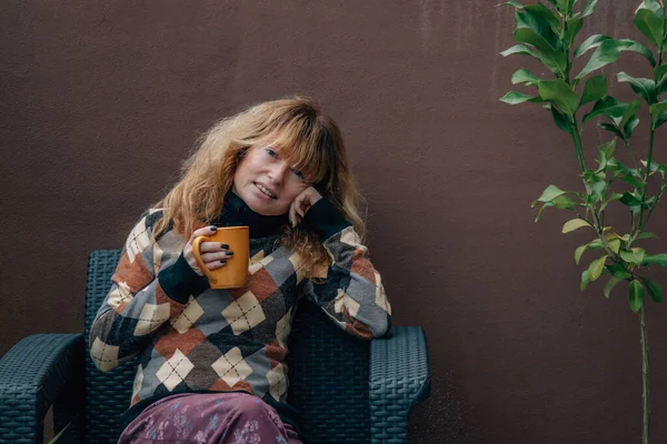 Evdeki mutlu kadın terasta kahve içiyor.