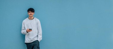 Sokak duvarında cep telefonu ve fotokopi alanı olan genç adam.