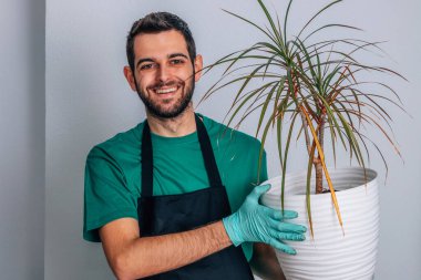 Bahçe işleri, iş kıyafetleri ve bitkileri olan bir adam.