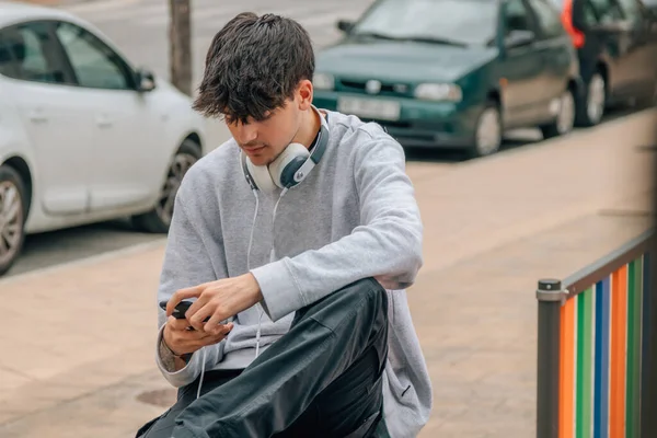 young millennial in the street with mobile phone and headphones