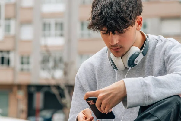 young millennial in the street with mobile phone and headphones