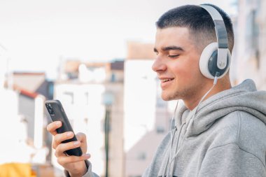 Cep telefonu ve kulaklıklı genç adam müzik dinliyor.