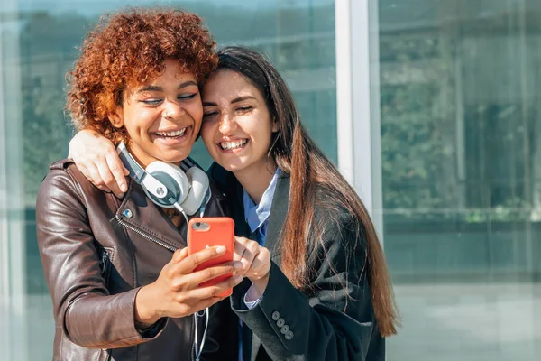 Dívky Usmívají Ulici Při Pohledu Mobilní Telefon — Stock fotografie