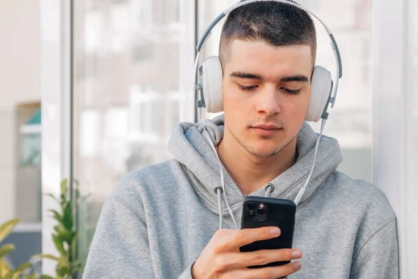 Cep telefonu ve kulaklıklı genç adam müzik dinliyor.