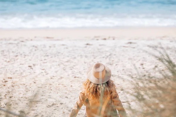 戴帽子的女孩坐在沙滩上的沙滩上 — 图库照片