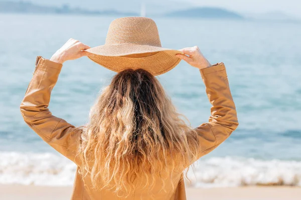海滩上戴着帽子的女人望着大海 — 图库照片