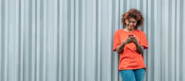 Sokak duvarında fotokopi alanı olan cep telefonu olan Afrikalı Amerikalı bir kız.