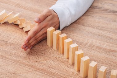 hand stops falling dominoes or wooden puzzle