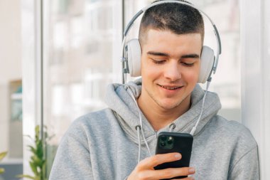 Kulaklık ve cep telefonu olan genç bir adam.