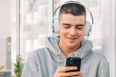 Kulaklık ve cep telefonu olan genç bir adam.